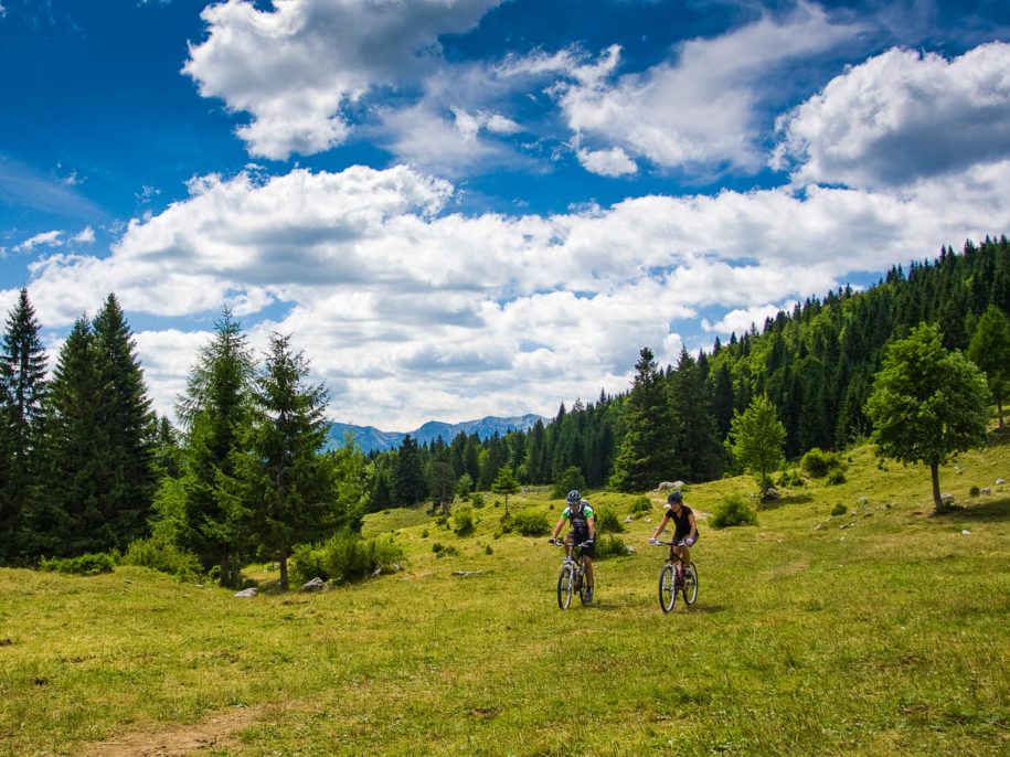 A couple on a mountain biking trip across the Uskovnica meadow in the Triglav National Park in Slovenia