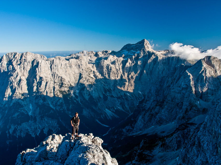 A hiker high above the alpine Vrata Valley in the Julian Alps with the Mt. Triglav and the massive Triglav Nort Wall in the background