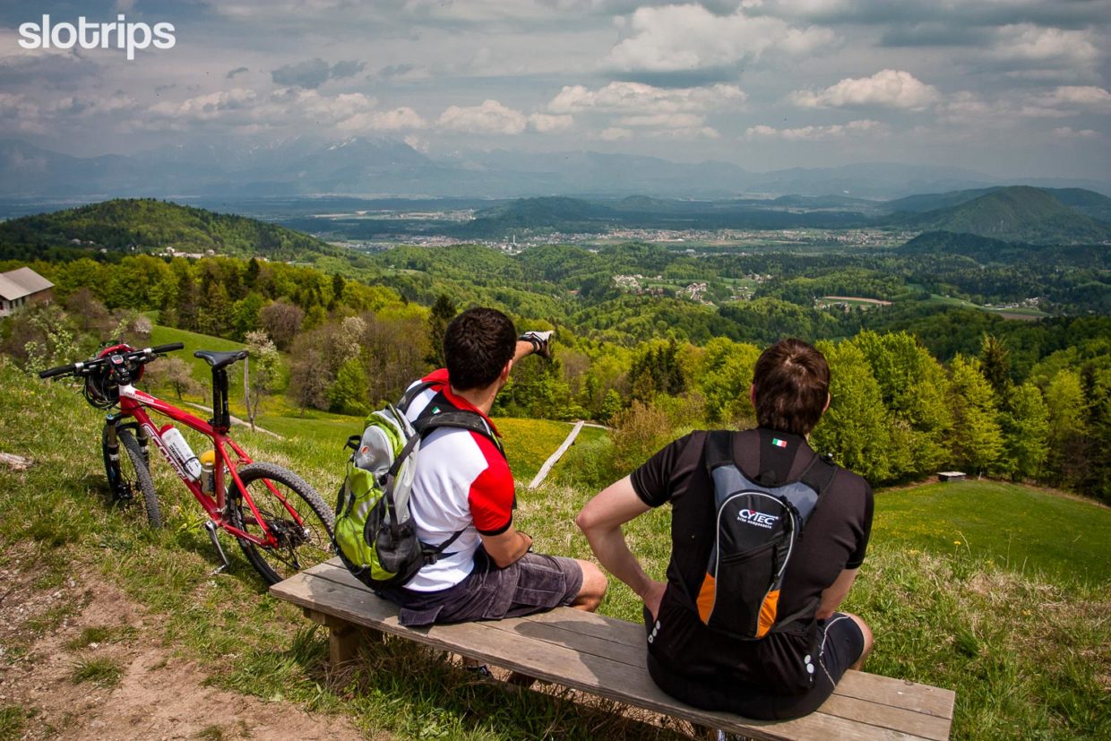 Two bikers on a mountain biking trip on Tosko Celo hill overlooking the Slovenian capital Ljubljana with Kamin-Savinja Alps in the background