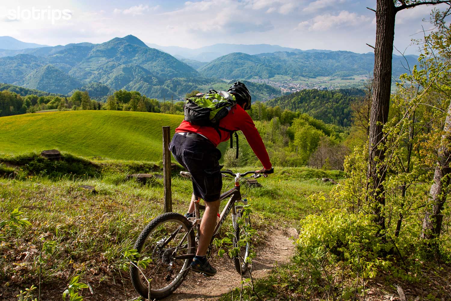 A mountain biker descending on a single track close to Ljubljana, Slovenia with Polhov Gradec Hills in the background