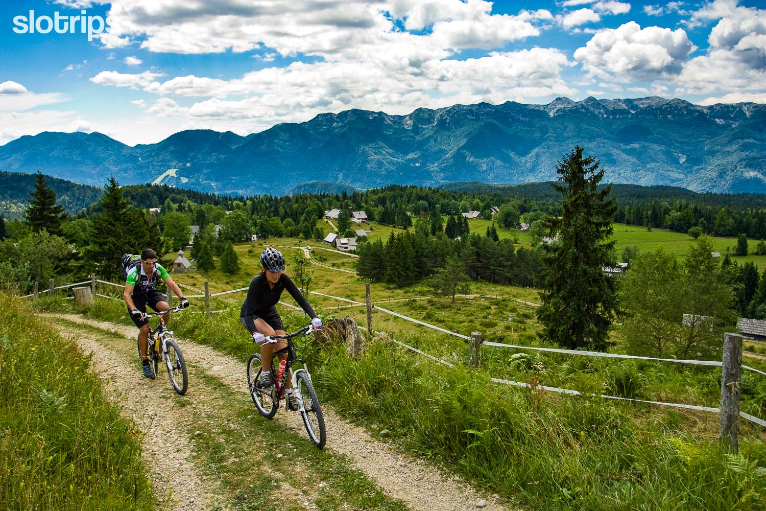 A couple on a mountain biking trip in the Julian Alps crossing an alpine pasture in the Slovenia Alps