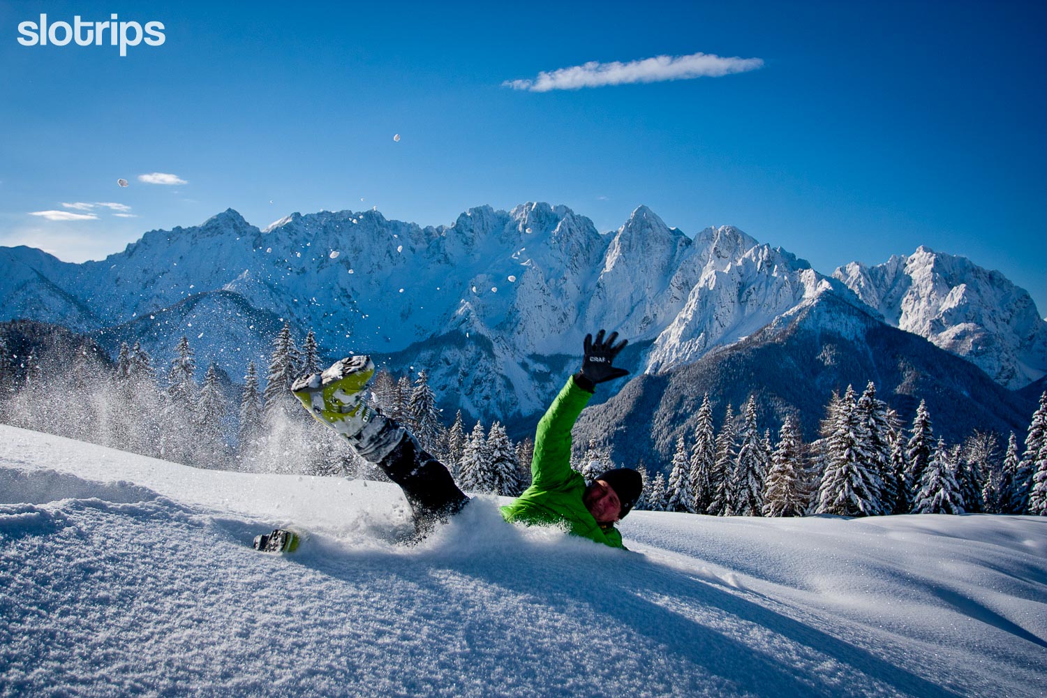 A happy hiker enjoying the fresh snow on Karawanks Mountain Range on the border with Austria with the highest peaks of the Julian Alps in the background