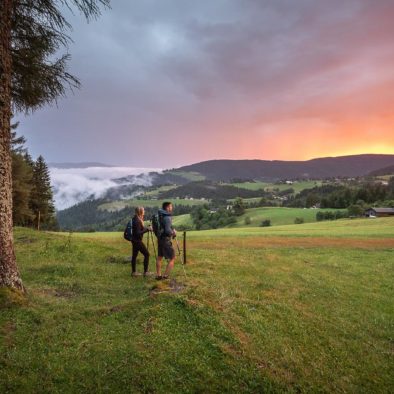 A couple on a walking trip across Pohorje hills enjoying colorful sunset in the countryside of Rogla.