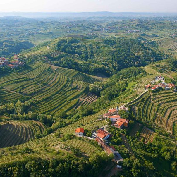 Authentic villages scattered across the rolling hills intertwined by the vineyards and low traffic asphalt roads in Goriska Brda wine hills, Slovenia