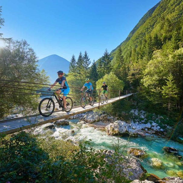 A group of mountain bikers across the hanging bridge across the Soca river in the Soca valley in Julian Alps in Slovenia