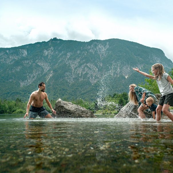 A family with young kids playing and splashing in the Bohinj Lake in the Triglav National Park, Julian Alps, Slovenia