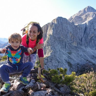A happy family on a mountain ridge with a footpath over a scree slope and Mt. Mala Mojstrovka in the background in Julian Alps in Slovenia