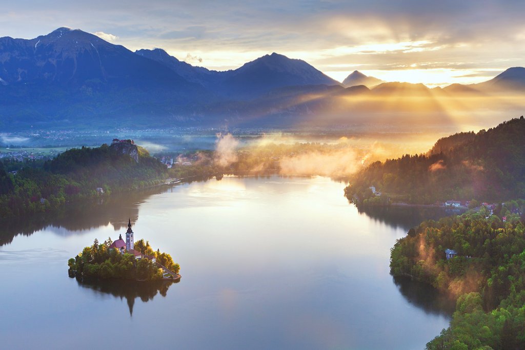 Lake Bled at dawn as seen from the Osojnica viewpoint with the Bled Castle, the Bled island and Tito's villa