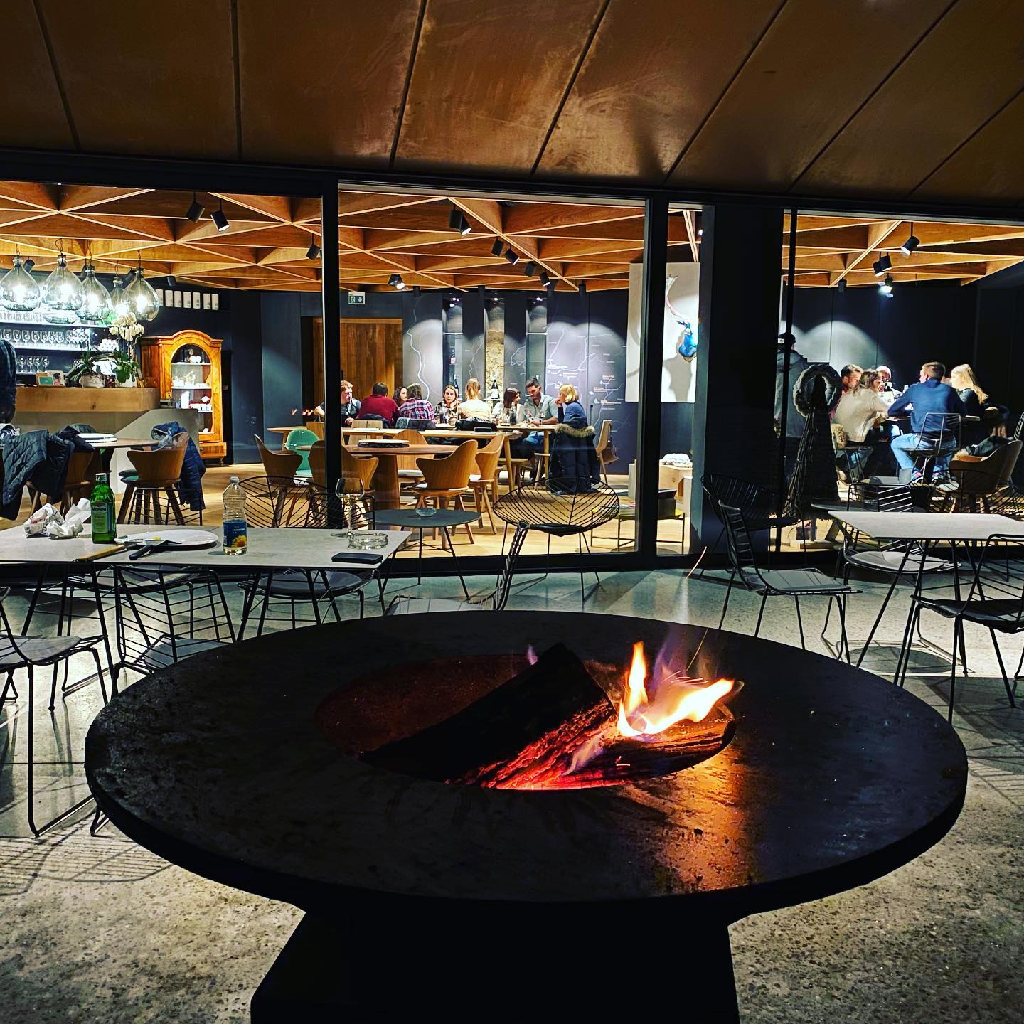 An open fire grill outside the wine tasting room at Edi Simcic wine producer from Goriska Brda wine region in Slovenia with two groups enjoying locally produced organic wine