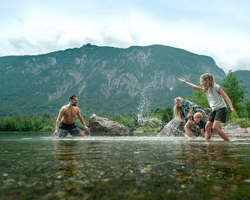 A family with young kids playing and splashing in the Bohinj Lake in the Triglav National Park, Julian Alps, Slovenia