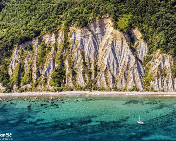 Sailing boat anchored in the blue lagoon below the cliffs of the Strunjan Nature Reserve.