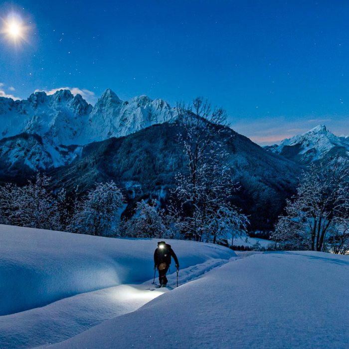 A ski touring skier on an early morning ascent to the Karawanks mountain range above the famous Kranjska Gora ski resort with Mt. Spik, Mt. Rokav and other mountains of the Martuljek mountain group in Julian Alps in the background